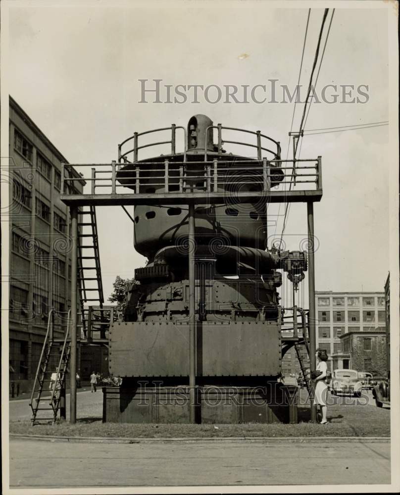 1949 Press Photo Woman stands and studies a huge General Electric turbine