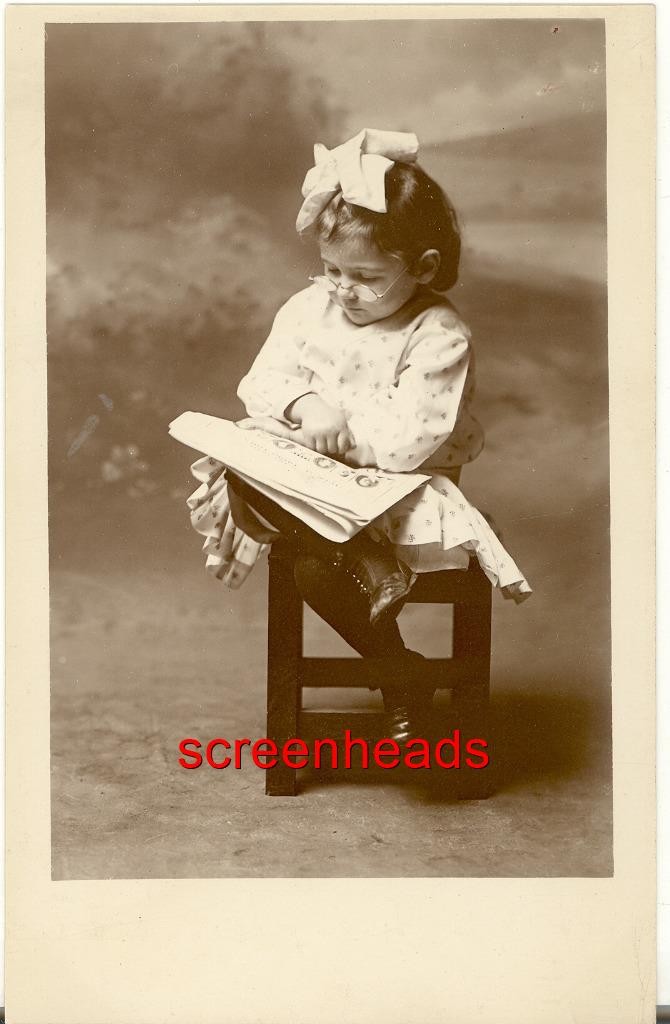 C1910 RPPC PHOTO YOUNG SPECTACLED GIRL CHILD READING MAGAZINE OR PAPER VG