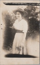 Woman in a hat and dress, posed outdoors RPPC Real Photo Postcard picture